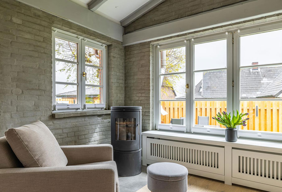 Wohnzimmer mit Holzofen und Blick in den Garten 